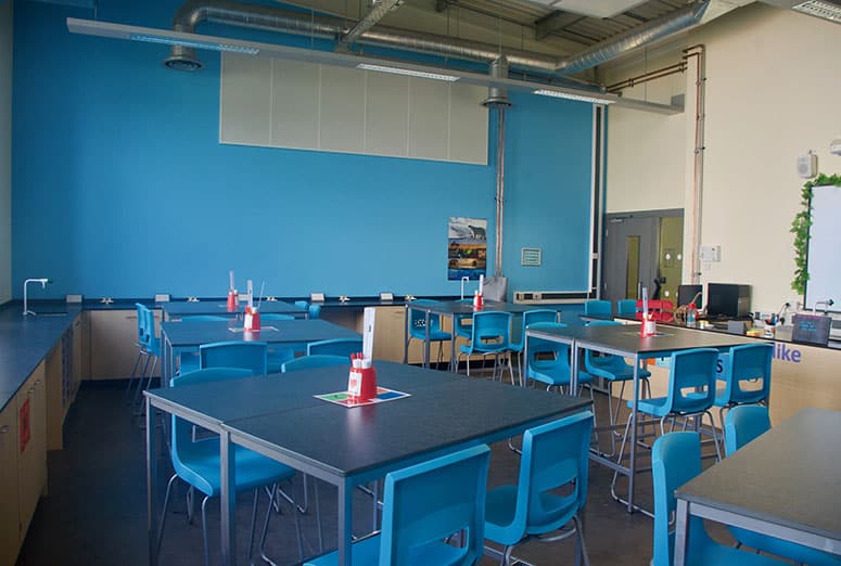 Blue contrast wall and co-ordinating stools in school science lab.