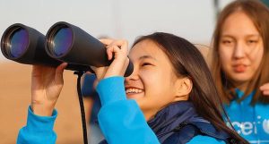 girls looking into binoculars engaging in science